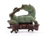 une statue représentant une grenouille assise sur une branche d'arbre