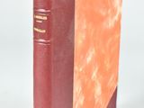 an old book with a red cover sitting on top of a white surface