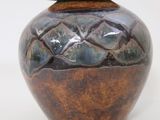 a brown vase with a lid sitting on a white surface