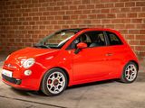 the small red car is parked in front of a brick wall
