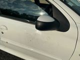 a white car with a black side mirror on the side of the road