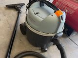 un aspirateur posé par terre à côté d'un bidon rouge
