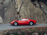 a red sports car driving down the road next to a cliff