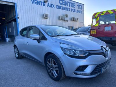 une voiture argentée garée devant un immeuble, avec un camion de pompiers en arrière-plan