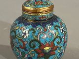 un vase bleu avec un couvercle doré posé sur une table