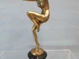 une statue en or représentant une femme, posée sur un socle noir