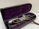 an old trumpet in a purple case sitting on a white surface