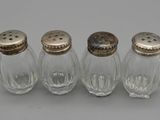trois salières et poivrières en verre avec des couvercles en argent