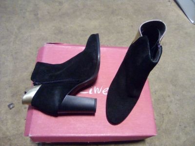 une paire de bottines en daim noir pour femme, présentée dans une boîte rose