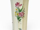 un vase avec des fleurs peintes dessus, posé sur une table