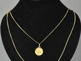 a gold necklace with a coin on a black mannequin