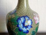 un vase vert orné de fleurs bleues, posé sur une table