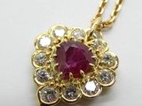 une photo d'un pendentif en rubis et diamants monté sur une chaîne en or