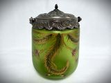 a green vase with a silver lid on a white table