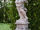 a statue of a boy playing a guitar in a garden