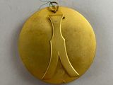 a close up of a gold medal with a dress on it
