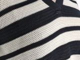 the back of a woman ' s sweater with a black and white striped design