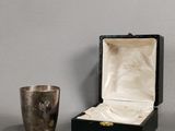 a silver cup sitting next to a silver cup on a table