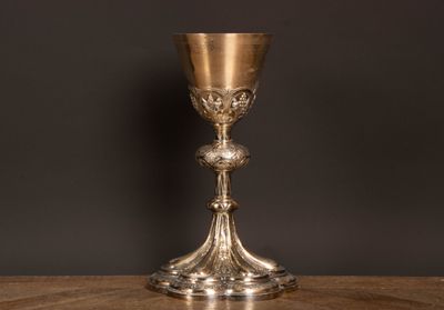 un gobelet ancien en argent posé sur une table en bois, sur fond noir