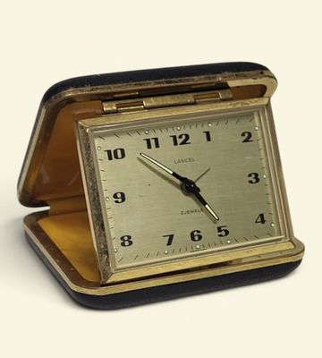 a small clock sitting in a case on a white surface