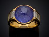 a close up of a gold ring with a blue stone and baguets