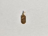 un petit pendentif en or représentant un visage, posé sur un fond blanc