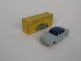 une petite voiture miniature posée à côté d'une boîte sur une surface blanche