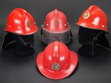 three red fire helmets are lined up against a black background