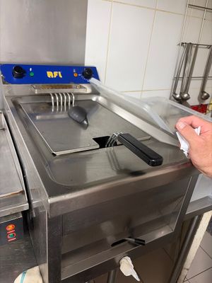 a man that is standing in a kitchen with a fryer
