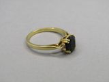 gros plan d'une bague en or contenant une pierre noire