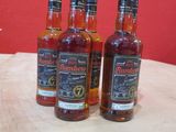 trois bouteilles de whisky sont posées sur une table devant un mur rouge