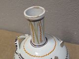 a white vase sitting on a table next to a wall
