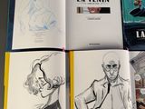 several books are open on a table with a drawing of a man and a woman