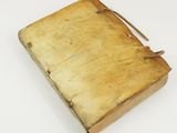 an old book is sitting on a white surface with a brown strap