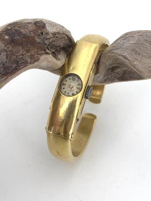 a gold ring with a watch on it sitting on top of a piece of wood