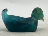 a glass duck that is sitting on the ground