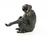 statue of a man sitting on a rock with his legs crossed