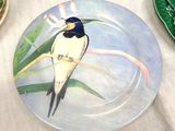a plate with a bird painted on it sitting on a table