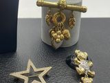 three gold and silver jewelry items sitting on top of a black table