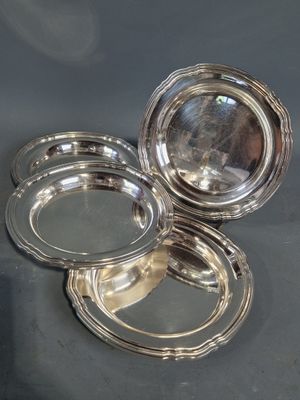 trois assiettes plaquées argent posées sur une table avec un fond noir