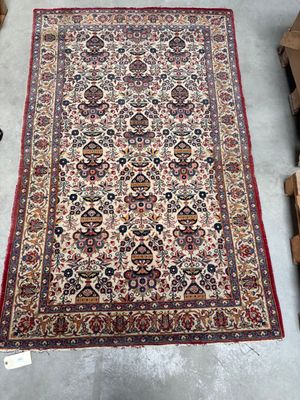 Un grand tapis oriental est exposé dans un entrepôt