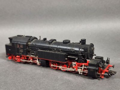 une locomotive noire et rouge sur un fond gris