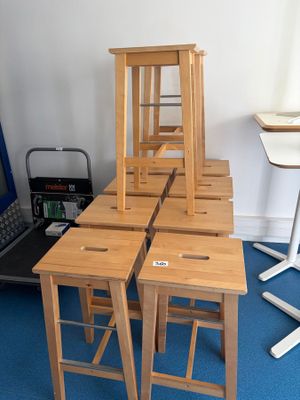 plusieurs tabourets en bois posés sur un tapis bleu devant un ordinateur portable