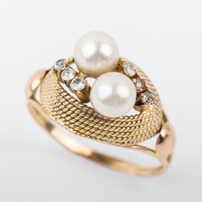un gros plan d'une bague en or ornée de deux perles et de diamants
