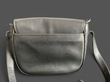 silver leather cross body bag with adjustable strap on grey background