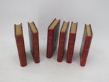 six red books lined up in a row on a white surface