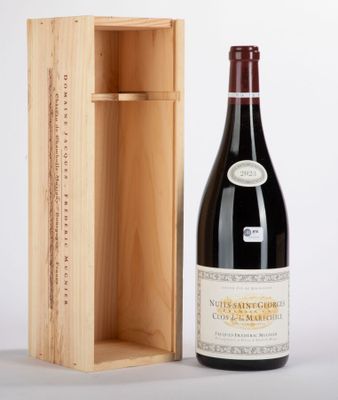 the bottle of wine is next to the wooden box on the table