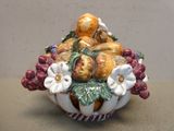 un bol en céramique contenant des fruits et des fleurs