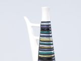 un vase blanc orné de rayures noires et bleues