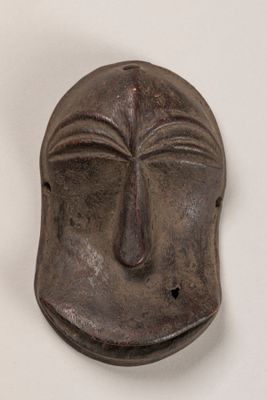 un masque métallique sur lequel est représenté un visage, posé sur un fond blanc